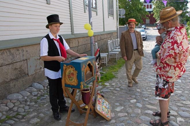 Jami Karvonen Tammisaaresta tuli kesäksi Kaskisiin ja pääsi naapurikaupungin maalaustapahtumaan pyörittämään kaskislaisen vaarinsa Harri Karvosen posetiivia. Kristiinan kantakaupunkilainen Teijo Laaksonen kuuntelee soittoa seitsemän kuukauden ikäisen teuvalaisen Wenneri Lehdon kanssa. KUVA: AUNE WARONEN