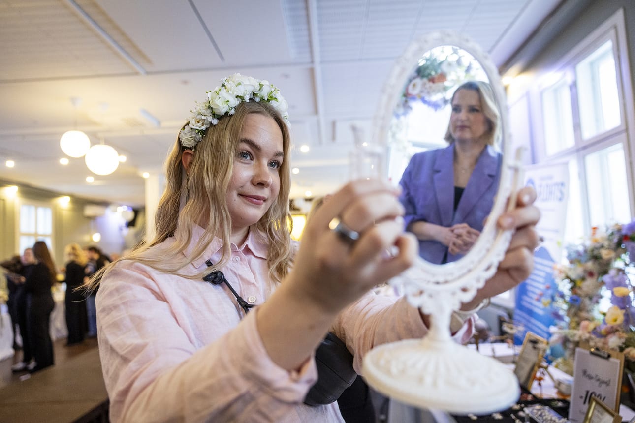 Roosa Mikkonen sovittaa häämessuilla hiuspantaa. Peilikuvassa näkyvän Emma Jokikokon mukaan kukkahiuskorut ovat nykyään suosittuja.