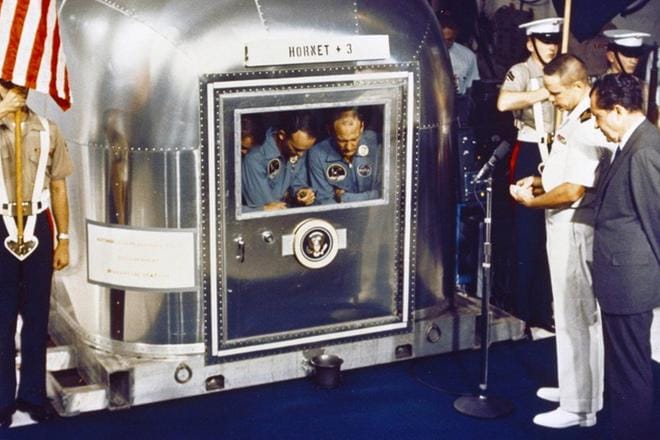Lentotukialus USS Hornetin (CV-12) sotilaspappi John Piirto piti hartaushetken Apollo 11:n karanteenissa oleville astronauteille. Presidentti Richard Nixon kuuntelee kappalaisen vieressä. KUVA: NASA