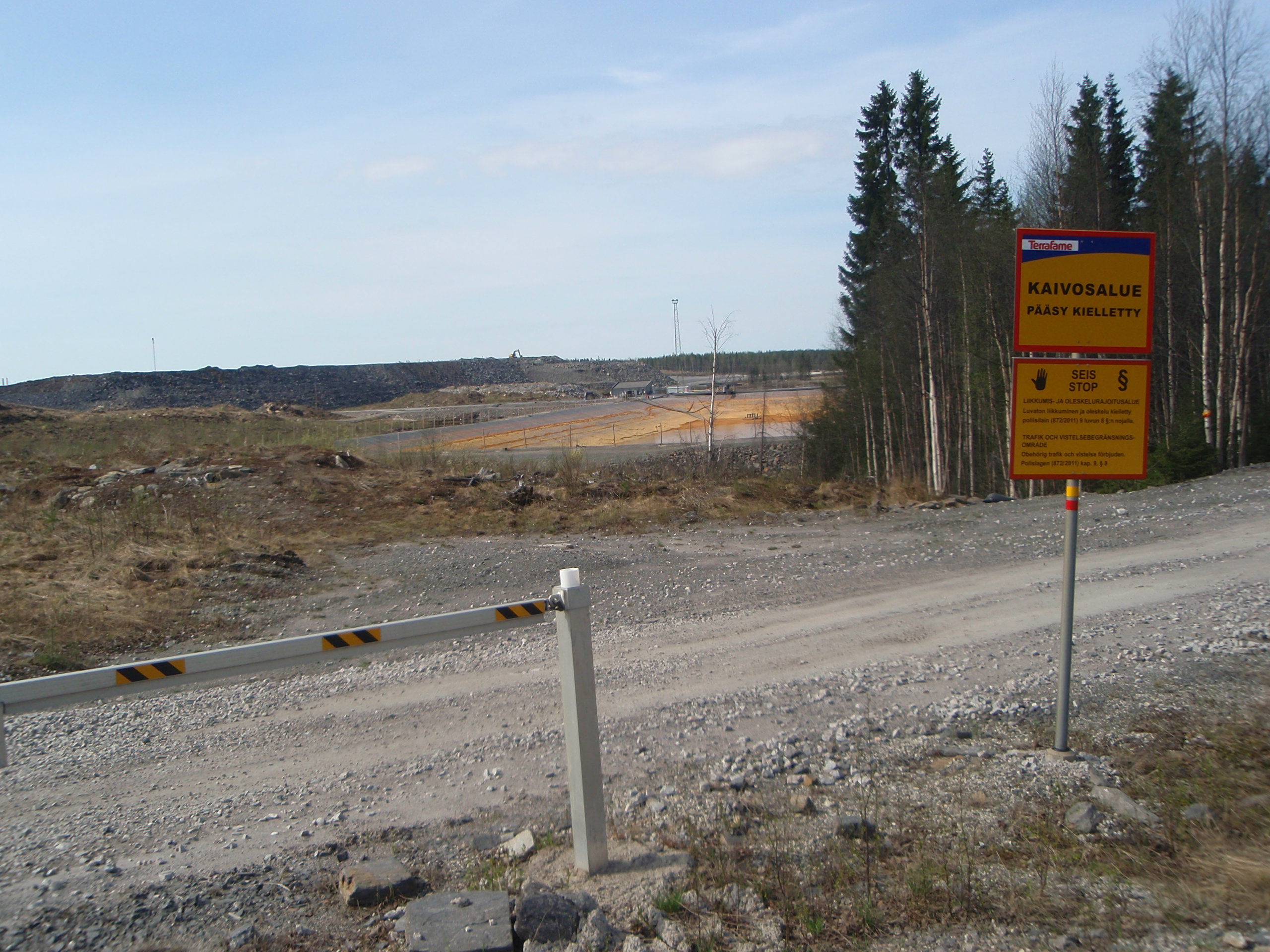 Talvivaaran kiistellyn kaivoksen jätevesien saostusallas päilyy kevätauringon paisteessa. Kyltti kertoo luvattoman oleskelun olevan kiellettyä kaivosalueella.