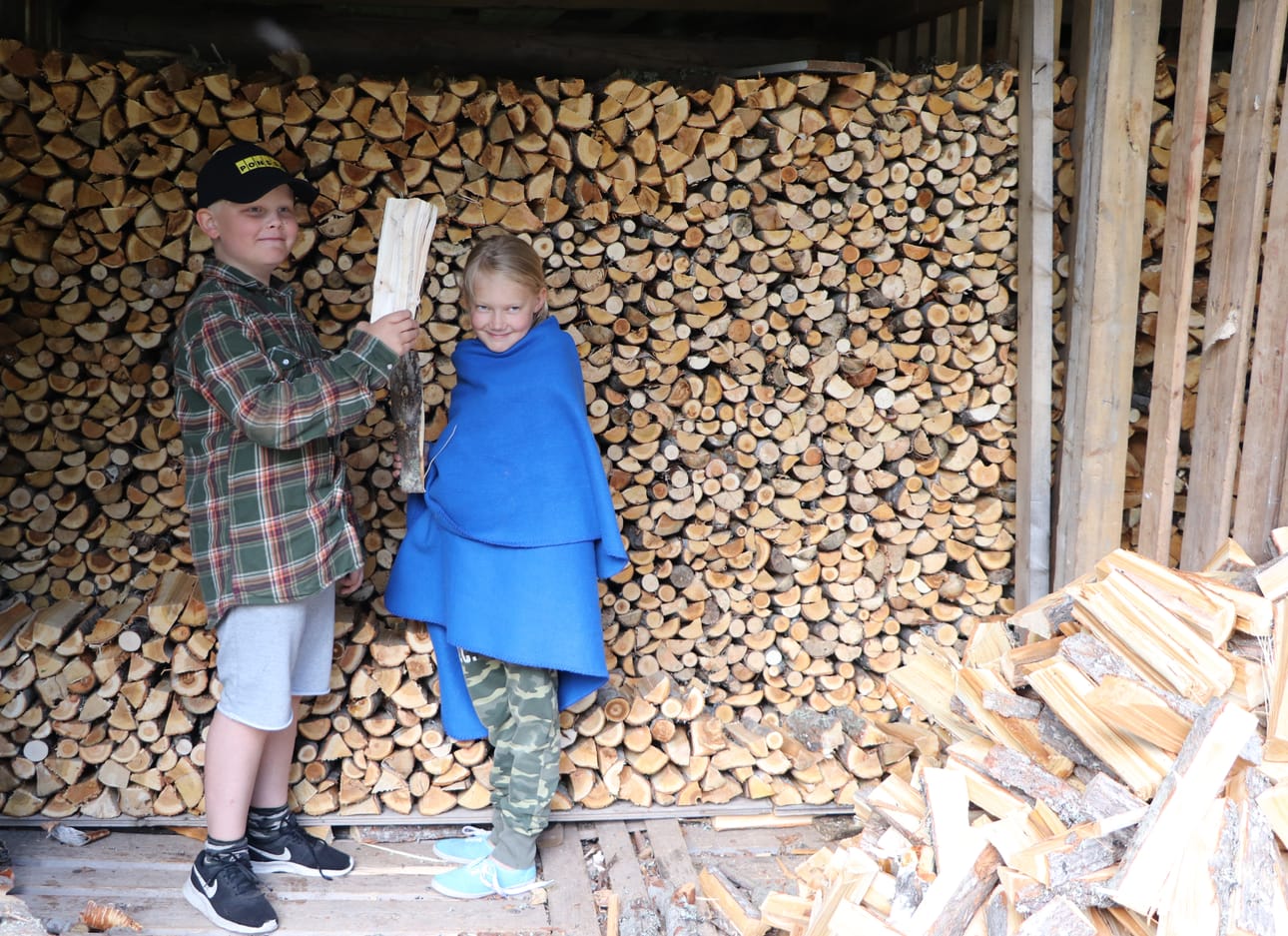 Mökillä halkohommat kuuluvat arkeen. Eeli Viksröm ja Riia Flink näyttävät valtavan halkopinon äärellä, miten hommia tehdään.