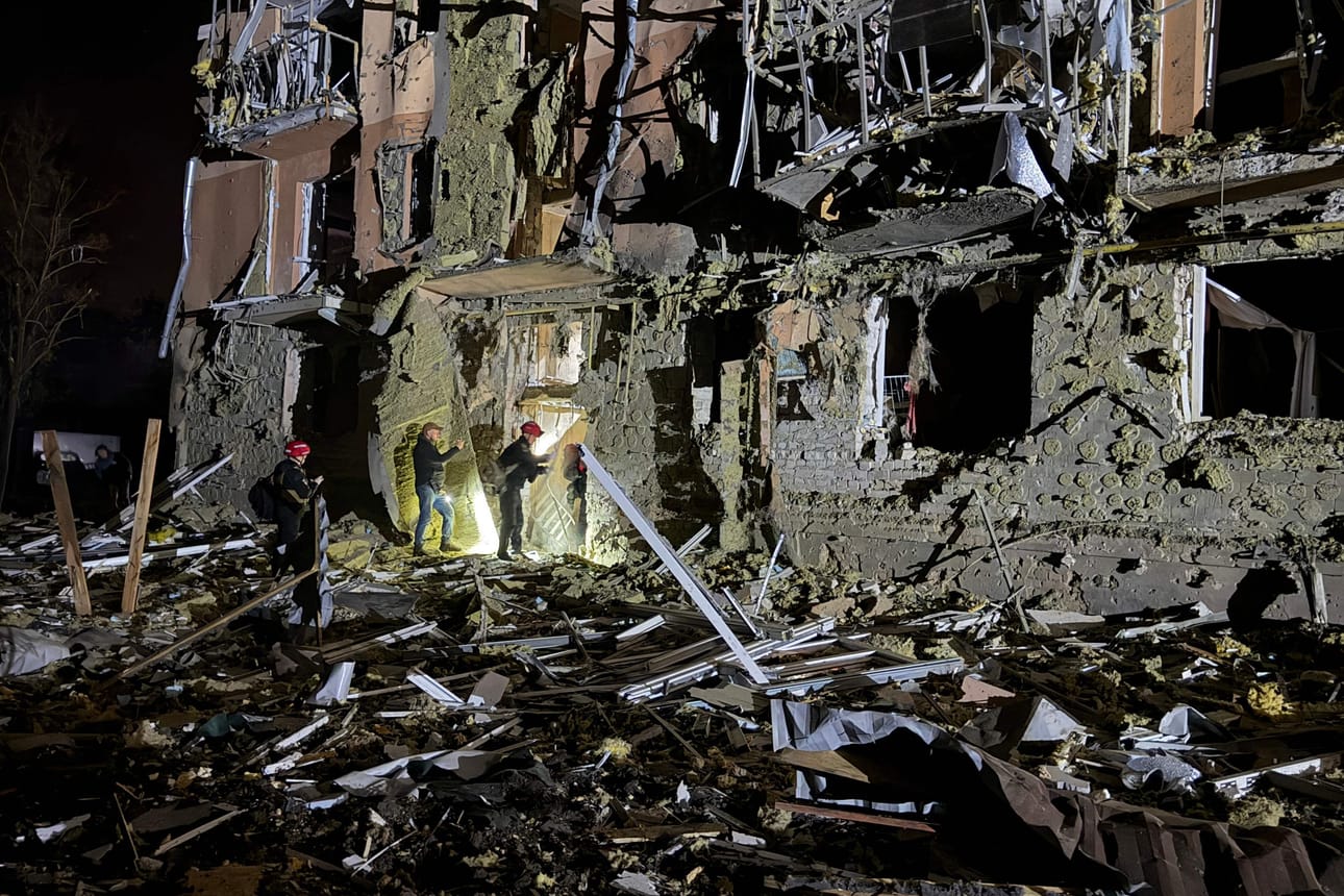 Ukrainalaiset pelastustyöntekijät työskentelevät Venäjän ohjusiskussa vaurioituneiden asuinrakennusten luona Zaporižžjassa.