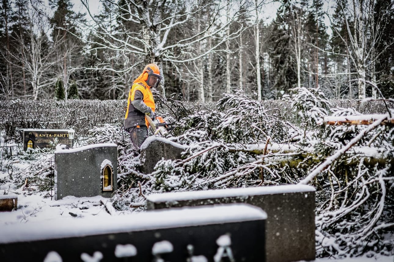Metsuri Jarkko Saari pilkkoi Törnävän hautausmaalle lauantain myrskyssä kaatunutta puuta.