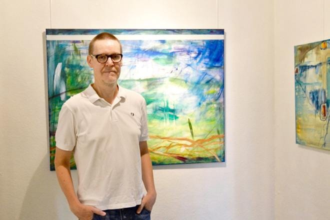 Kuvataiteilija Tapio Hirvonen taustallaan teos Sateen jälkeen.