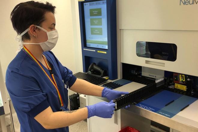Laboratoriohoitaja Hanna Saarimaa syöttää näytteet analyysilaitteeseen, joka antaa koronatestin tuloksen tunnissa. Kuva Virpi Kupiainen-Ämmälä