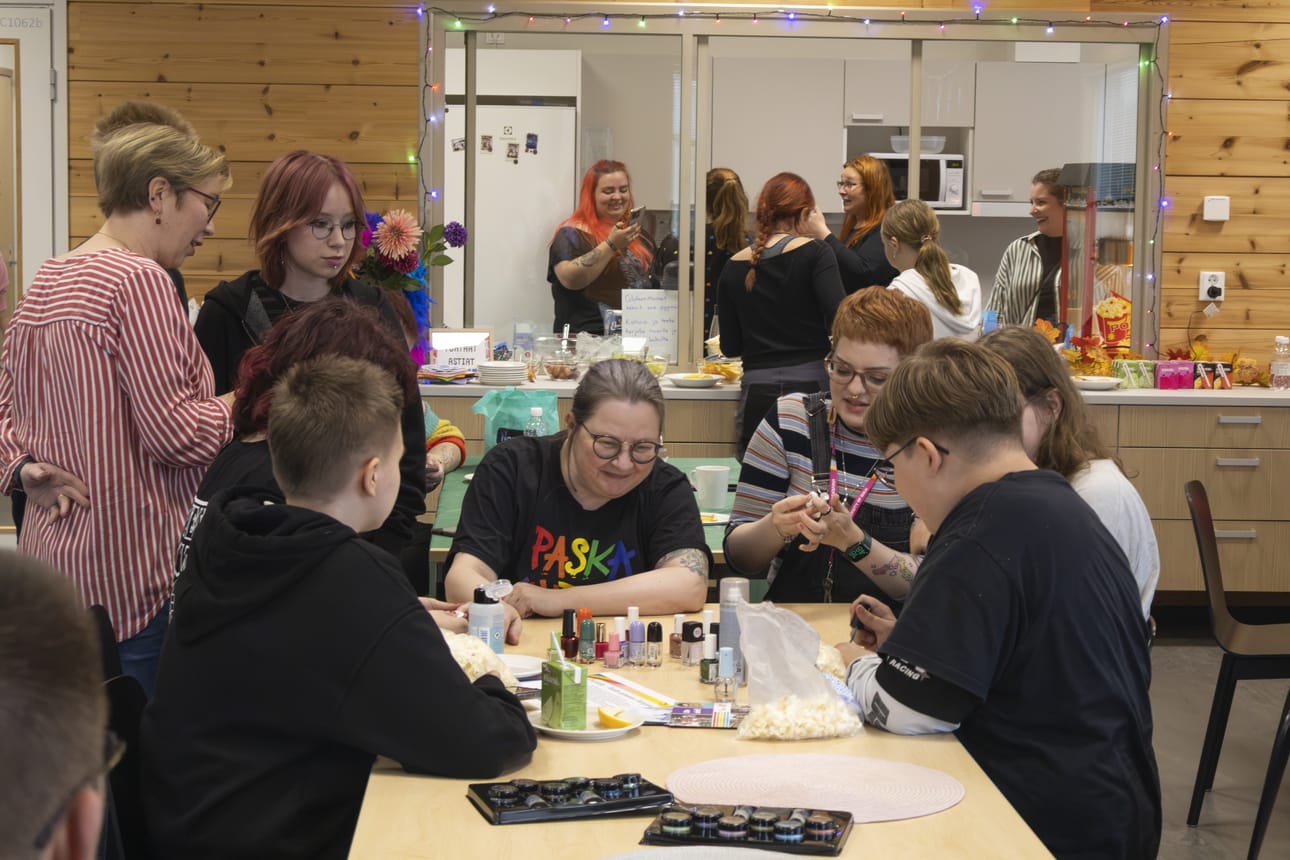 Illan aikana osallistujat muun muassa lakkasivat toistensa kynsiä. Pöydän päässä istuu Oulu priden päätuottaja Martu Väisänen.