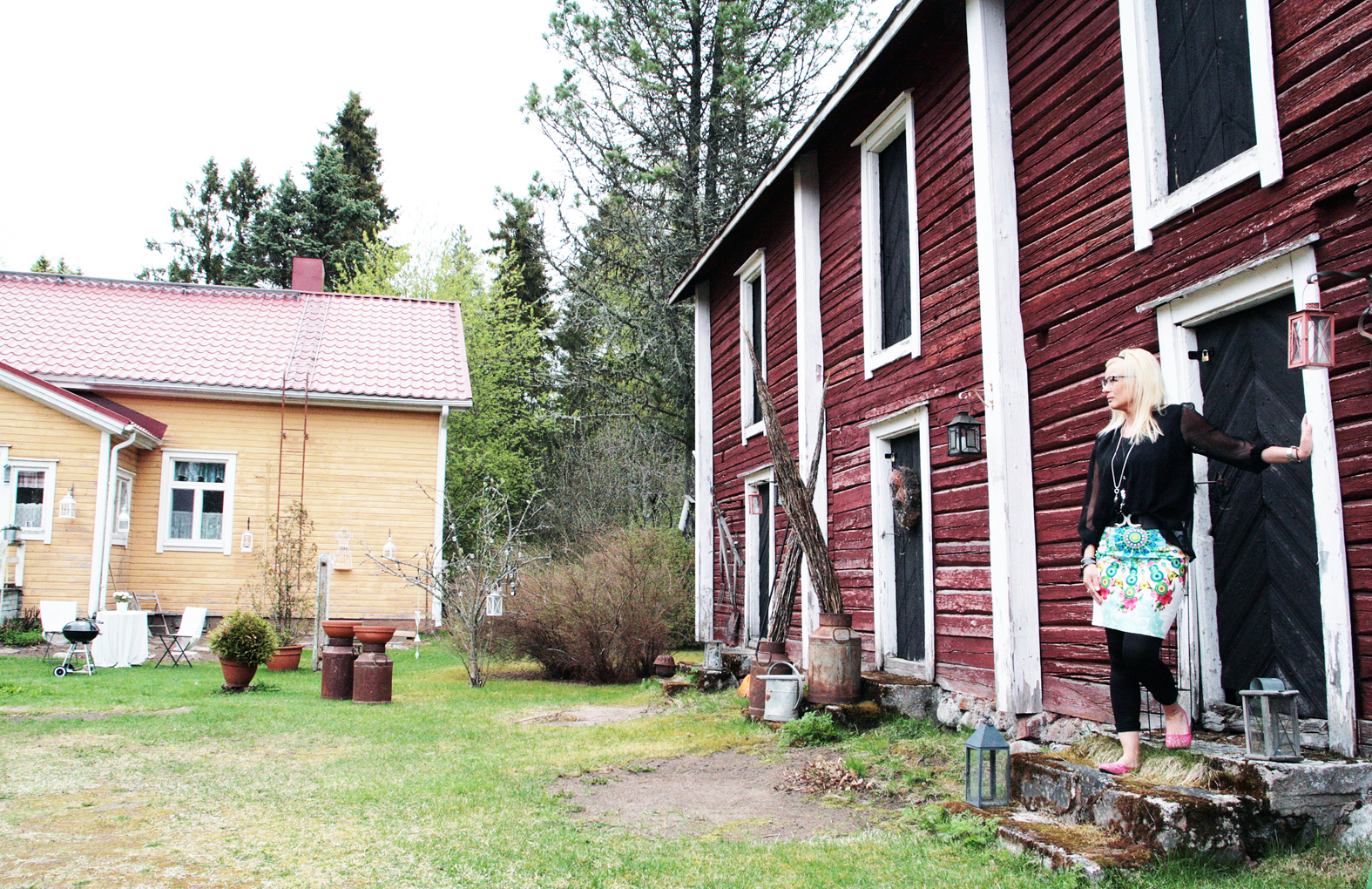 Sinikka Vuoti-Sarajärvi nojaa 1600-luvulla rakennettua aittaa vasten. Sen seinien sisältä on löytynyt paljon vanhoja esineitä, joita hän on käyttänyt sisutuselementteinä. - Aikoinaan aittaa käytettiin sekä nukkumiseen että viljan säilytykseen. Ja jossakin välissä se on ollut myös läpikulkuaitta. Toinen osa aitasta on vain hävinnyt vuosien aikana.