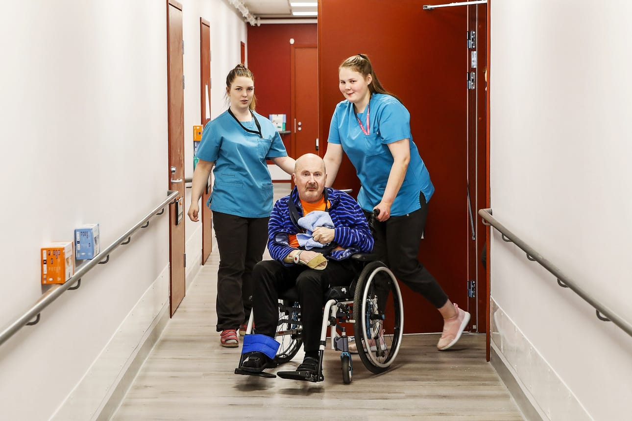 Lähihoitajaopiskelijat Emmi Sirniö, 20 (vas.), ja Vera Kellokumpu, 17, avustavat Pekka Valkosta, 62, Rovaniemellä. Sirniö ja Kellokumou kertovat olevansa kutsumusammatissa. He pitävät soveltuvuuskokeita tärkeänä: "vaativa ala ei sovi kaikille".