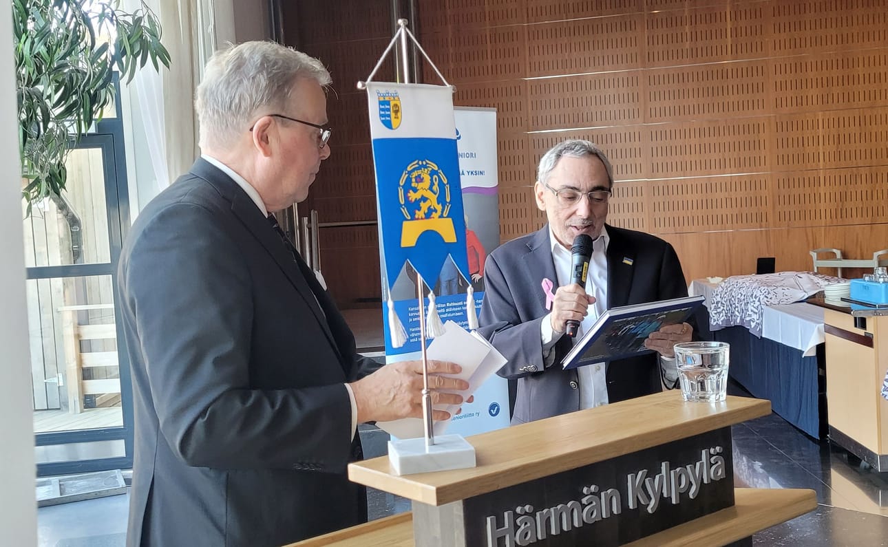 Ben Zyskowicz sai Ylihärmässä lauantaina Erkki Honkalalta Seinäjoen kansalliset seniorit ry:n pari vuotta sitten julkaiseman Meissä virtaa riittää -kirjan.