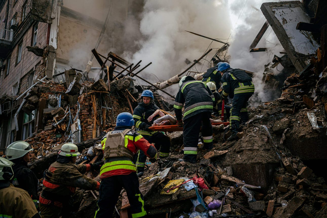 Ukrainalaiset palo- ja pelastustyöntekijät kantavat Venäjän iskussa kuolleen siviilin ruumista Zaporizhzhjan kaupungissa. LEHTIKUVA / AFP