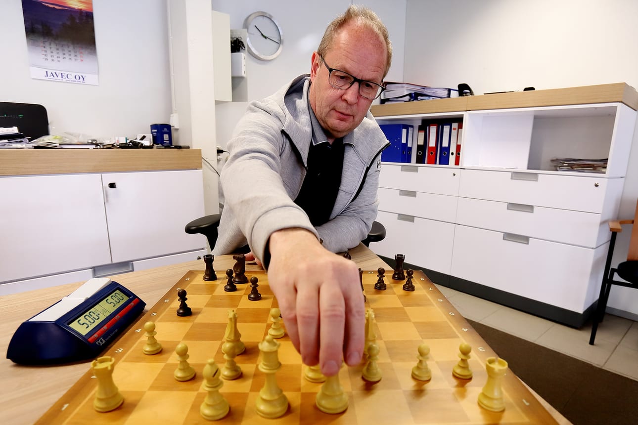 Heikki Sarkkinen asettelee shakkinappuloita työpaikallaan Raahen Autokulmassa.
