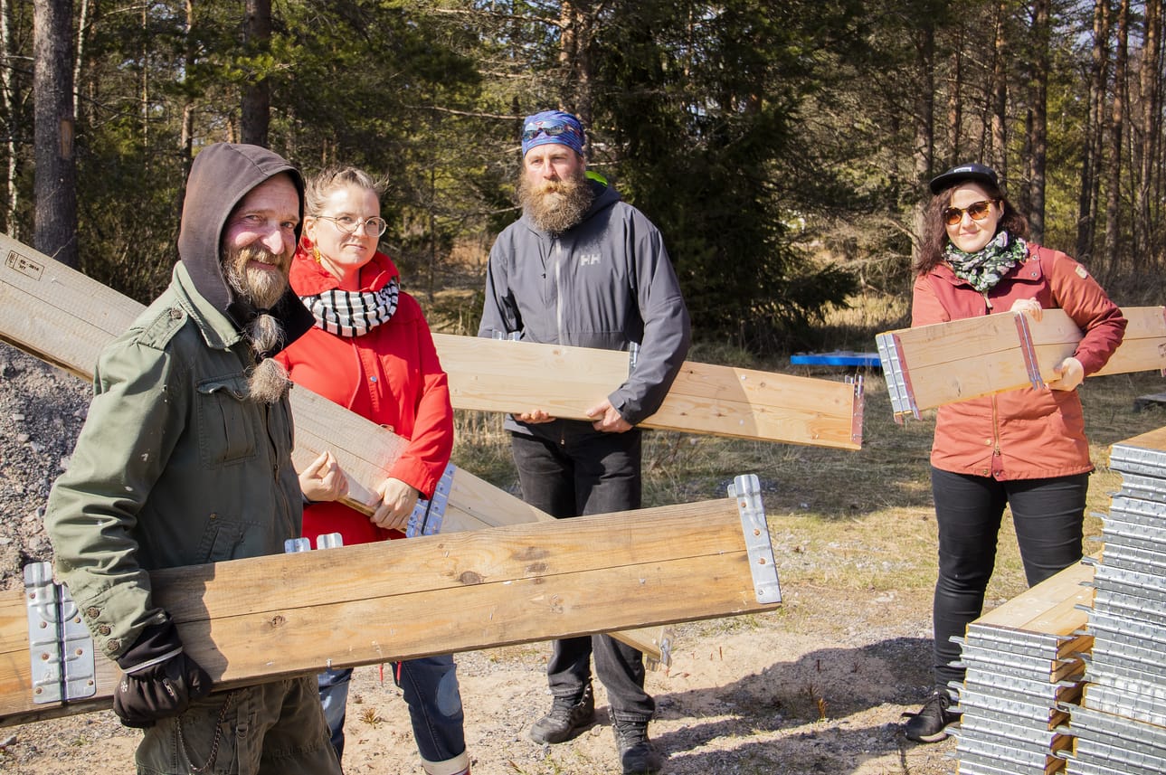Kari Tuhkanen, Tiina Laurila, Kimmo Sorvoja ja Liisa Louhela kuljettavat kasvatuslaatikoita yhteisöpuutarhaan, joka rakentuu koulun tontille jääkiekkokaukalon taakse.