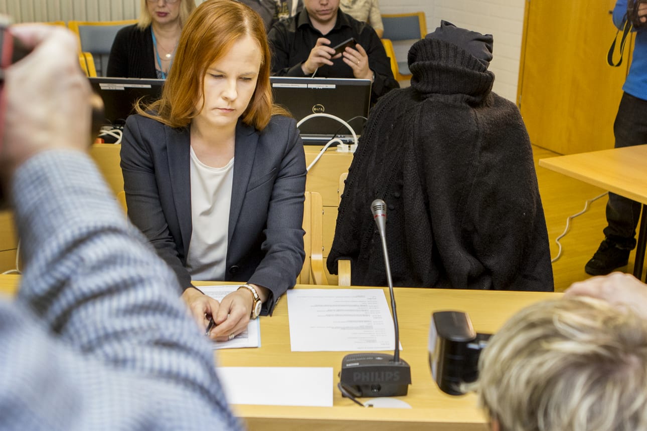 Syytetty peitti kasvonsa villavaatteella valokuvaamisen ajaksi viime joulukuussa pidetyssä oikeudenkäynnissä. Kuvassa on syytetyn lisäksi asianajaja Meeri Palosaari.