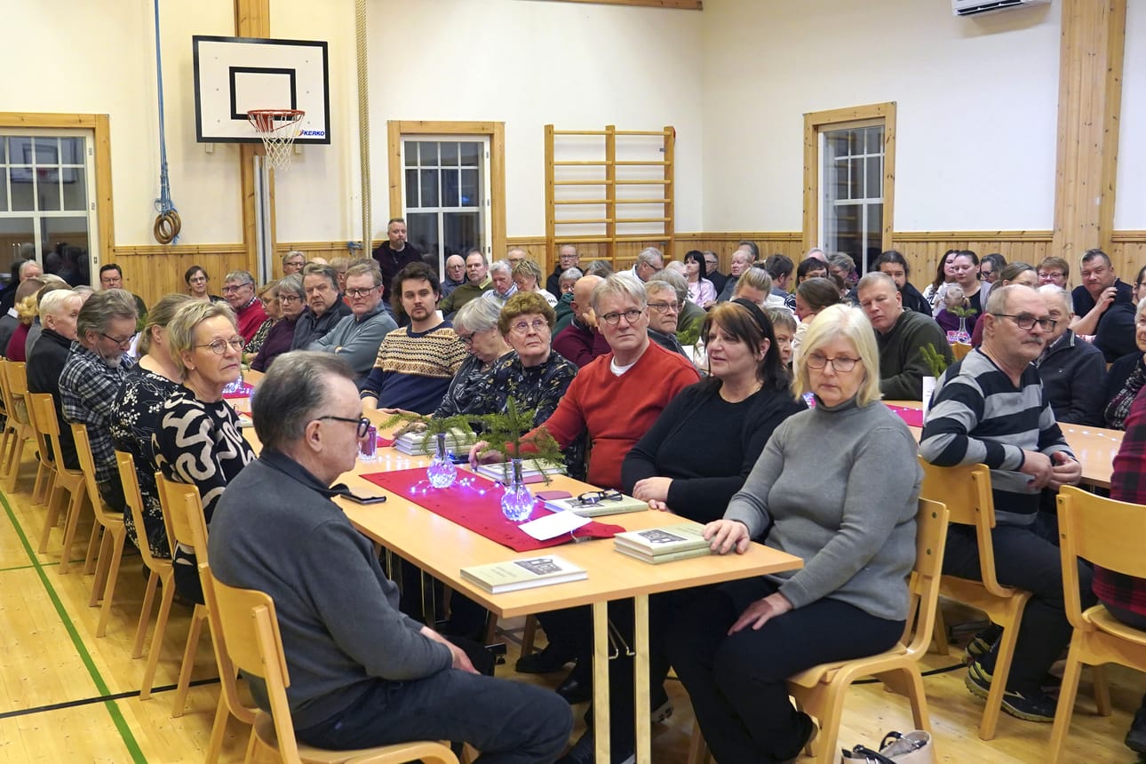 Menkijärven kyläkirjan julkisutus oli odotettu ja iloinen tapahtuma, vaikka ilmeet kuvassa näyttävätkin vakavilta. Kylätalo oli viimeistä sijaa myöten täynnä.