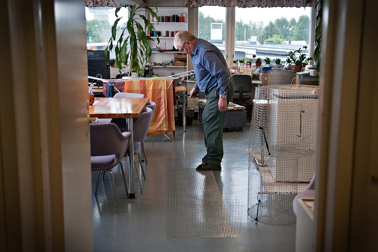Jouko Riekki joutuu valmistamaan katiskoita Hyvän mielen palveluaseman salin lattialla. Taustalla kuivat pyykit, ompelulankakerät, karaokelaitteiston vahvistin ja pakastin kertovat, mihin muuhun tilaa käytetään.