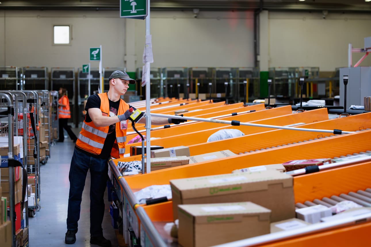 Työntekijä Eero Tikkanen nostelee robotin lajittelemia paketteja rullakkoon. Lajittelurobotteja aiotaan ottaa vähitellen käyttöön muissakin Postin logistiikkakeskuksissa.