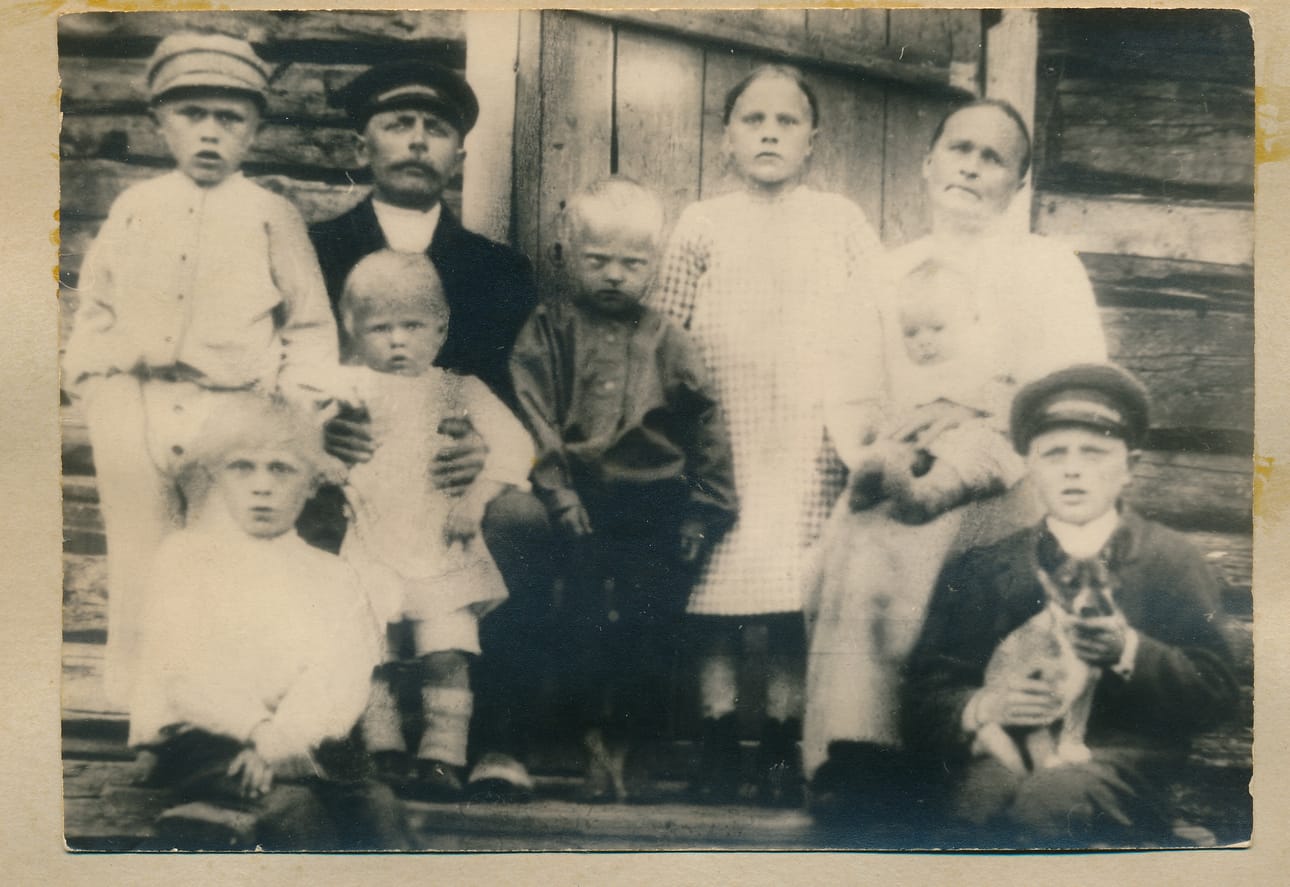 Tämä kuva on lasten ikähaarukasta päätellen vuodelta 1921 ja henkilöt vasemmalta lukien: Matti, Viljo, Vikke pitää kiinni kainaloista Eevaa, Lauri, Anni, Idan sylissä Hanna ja Erkki sylissään Tellu-koira. Nuorimmat lapset Laura ja Eero ovat syntyneet myöhemmin. Kuva on ajalta, jolloin perheen talous oli tiukilla. Ida-äiti on neulonut säkkikankaasta koltut tytöille ja kenkiä käytettiin vuorotellen.