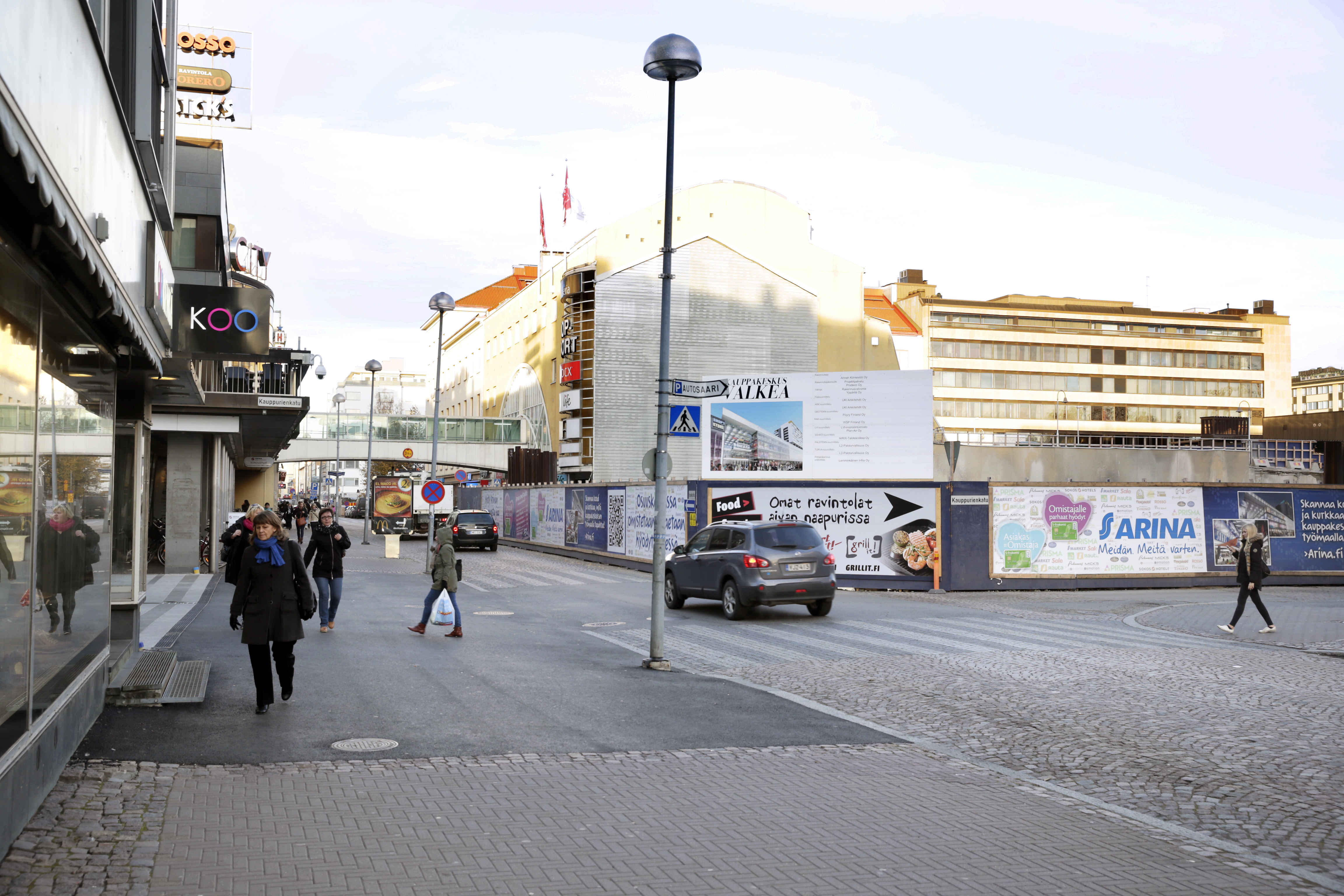 Tämänhetkinen näkymä Isollekadulle Kauppurienkadun risteyksestä. Katteen reuna olisi suurin piirtein rakennustyömaan aidan kohdalla.