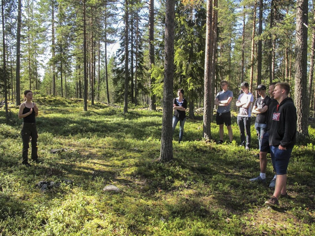 Arkeologi Laura Ohenoja opastaa lukiolaisryhmää Rajakankaan jätinkirkolla.