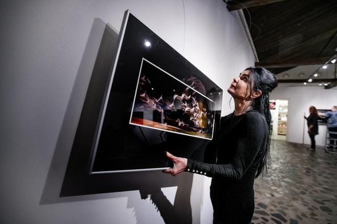 Jaana Kotamäki ripustaa Varikkogallerian seinälle Vapaus-kuvaa, joka on otettu Mynämäen Mietoistenlahdella syyskuussa 2013. Kuvassa on lähellä meren pintaa lentävä joutsenparvi, jota Kotamäki on kuvannut pitkällä suljinajalla. KUVA: JAAKKO ELENIUS