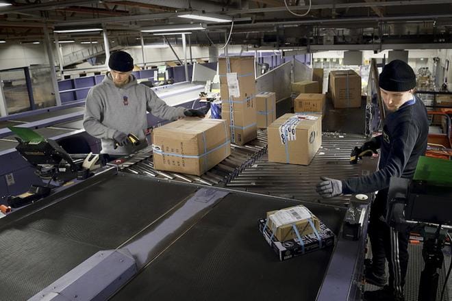 Atte Tikkanen ja Tomi Tikkanen lajittelevat paketteja Postin Lajittelukeskuksessa Seinäjoen Kapernaumissa. Sesonkiaikaan lajittelukeskuksen kautta kulkee yhteensä 20 000 pakettia vuorokaudessa. KUVA: HEIKKI HAKANEN