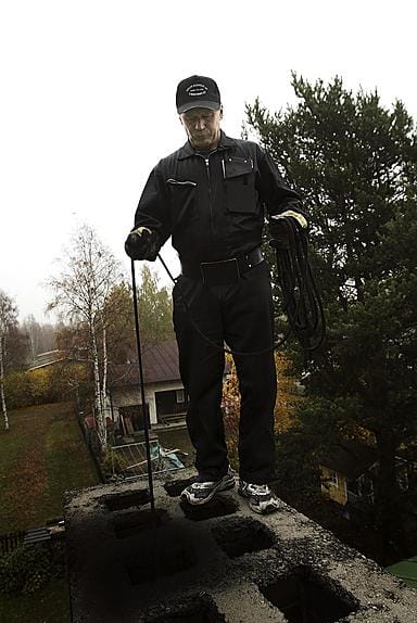 Nuohooja Jorma Perätalo nousee tottuneesti ja varmoin ottein katolle, vaikka syksyisin nuohoojille sattuu eniten liukastumisia ja putoamisonnettomuuksia.