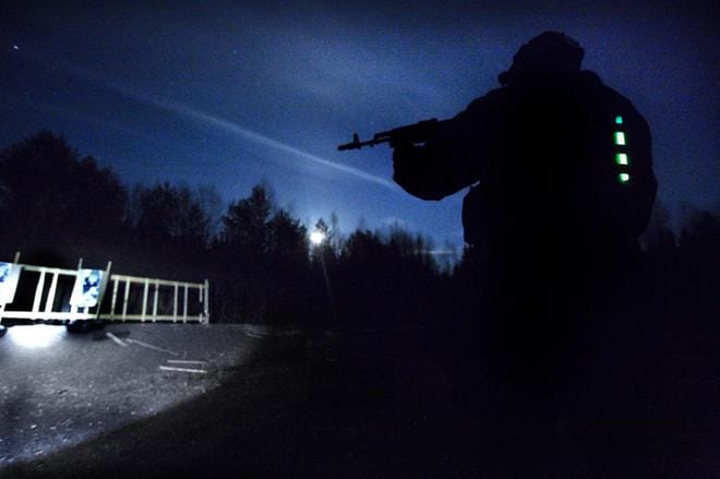 Asevalo ja täysikuu valaisevat Kivijärven ampumaradalla. Reserviläisillä on selässään valotikut, jotta he näkyvät pimeässä. Kuvat: Eetu Sillanpää