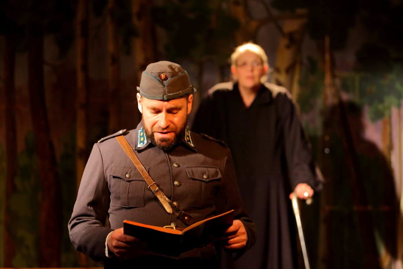 Sotilas (Leo Hänninen) lukee sotapäiväkirjasta Aaro Aronahon kaatumispäivän merkintöjä. Taustalla Impi Aronaho (Päivi Tuomainen).