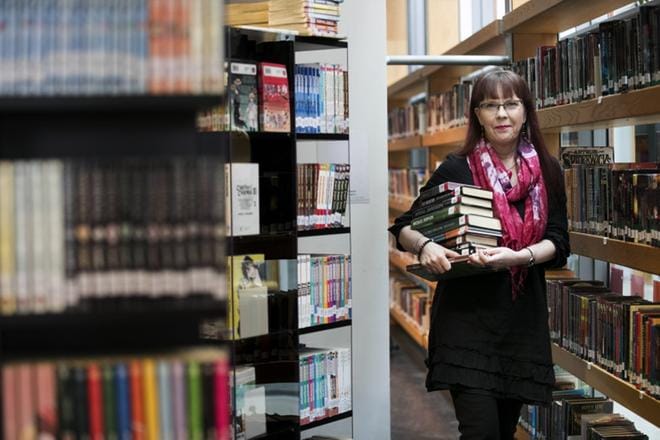 Sirkka-Liisa Sjöblomin kainalossa on pino hänen suomentamiaan kirjoja. Kaikkiaan niitä on noin 160, ja viihdelukemistoa vielä lisäksi. Suomentajan ura on kestänyt liki 30 vuotta. KUVA: MINNA ANTILA