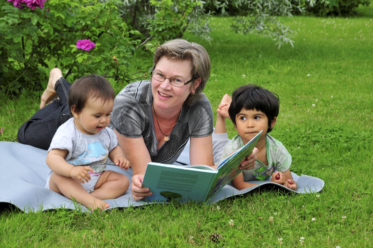Leena Rantala mieleisessä puuhassa, lukemassa kirjaa rakkaille lapsenlapsilleen Annille ja Laurille.