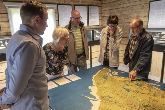Kurikka-seuran puheenjohtaja Olavi Kandolin (vas.) ja muu yleisö kuuntelee Veikko Myllyniemen selostusta 7000 vuoden takaista aikaa kuvaavasta topografia-kartasta. Kartan on valmistanut Eino Korpilahti. KUVAT: JUHO KORPELA