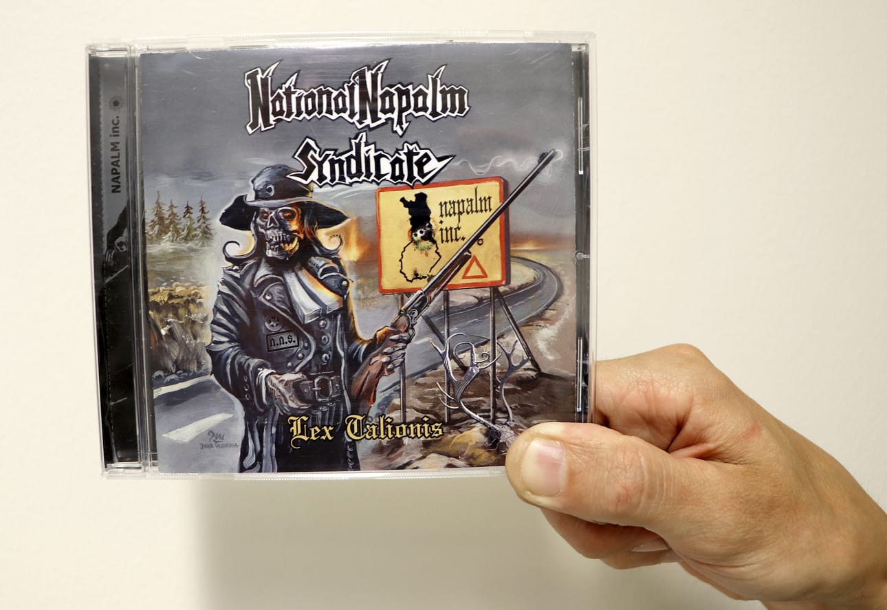 Tilaustöissä aihe ei ole vapaa. Pudasjärveläislähtöisen National Napalm Syndicaten LP vuodelta 2014. Kuvan pyssymies on yhtyeen ”maskotti”. Poronhoitoalue-liikennemerkissä yhtyeen jäsenten silloiset asuinpaikat luodinreijillä merkittynä.