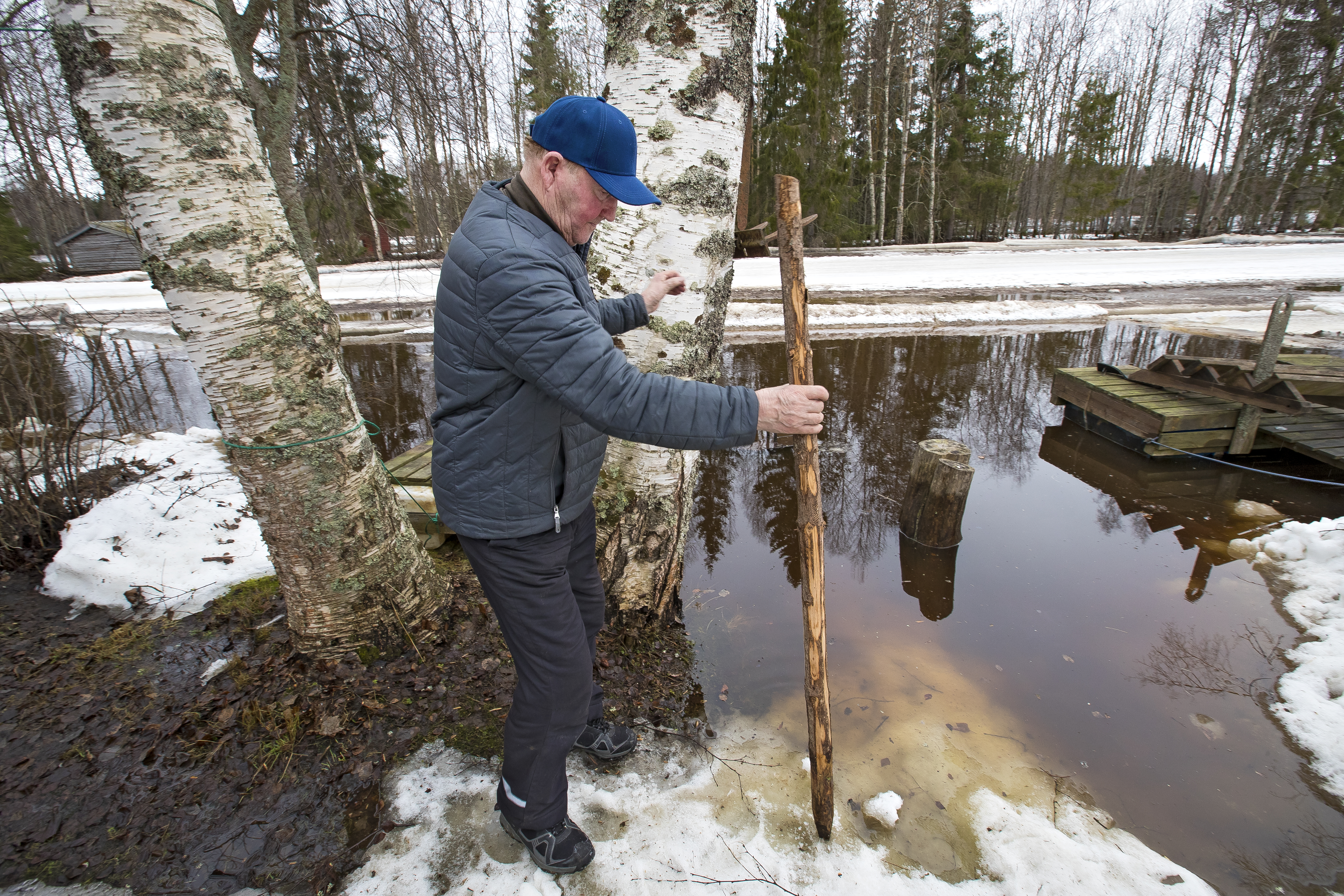 Jorma Halunen mittaa veden korkeutta mittakepillä.