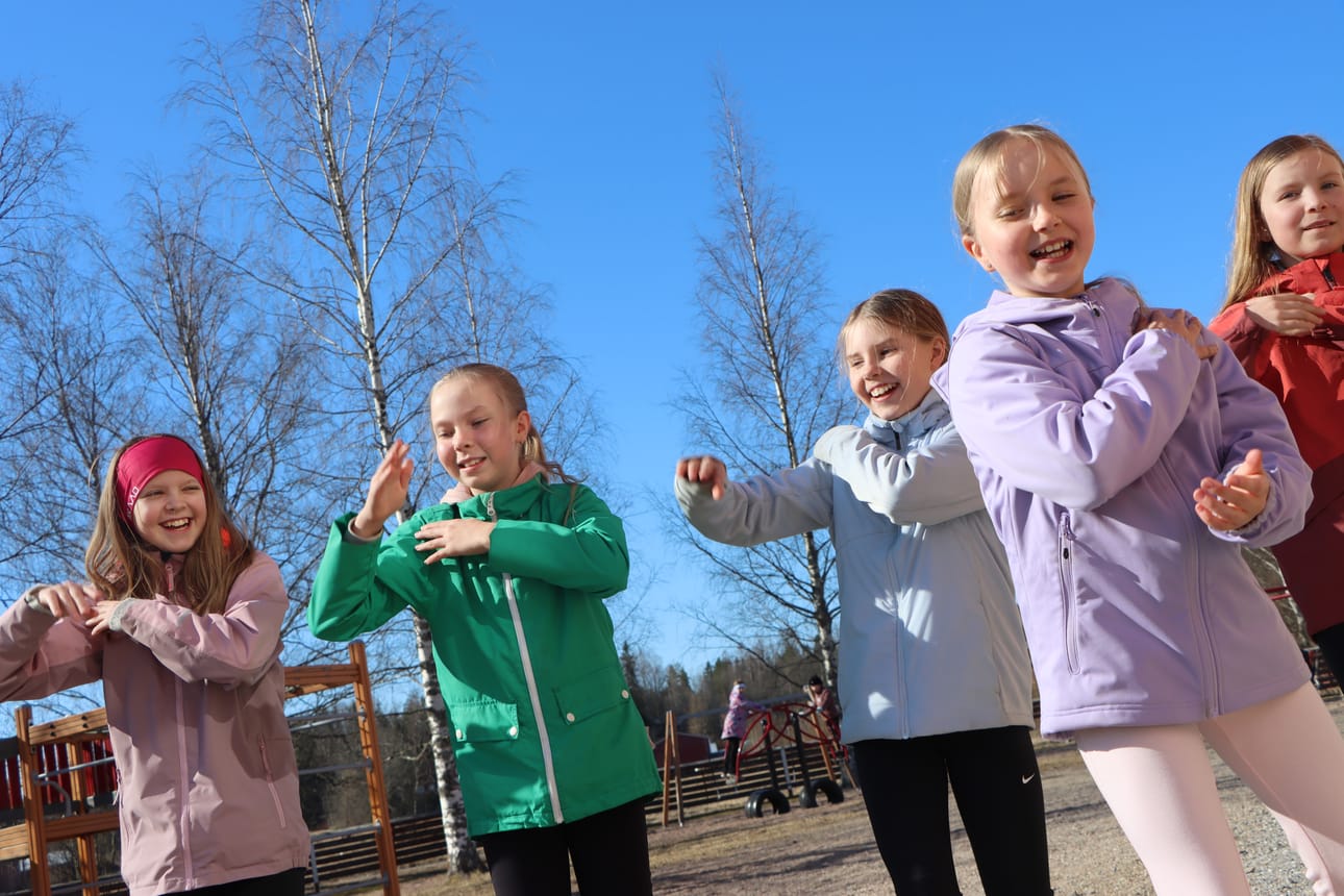 3.- ja 4.-luokkalaiset tytöt tanssivat kevätauringossa alakoulun välituntialueella hieman sambaa, johon oli sekoitettu myös Macarenaa.