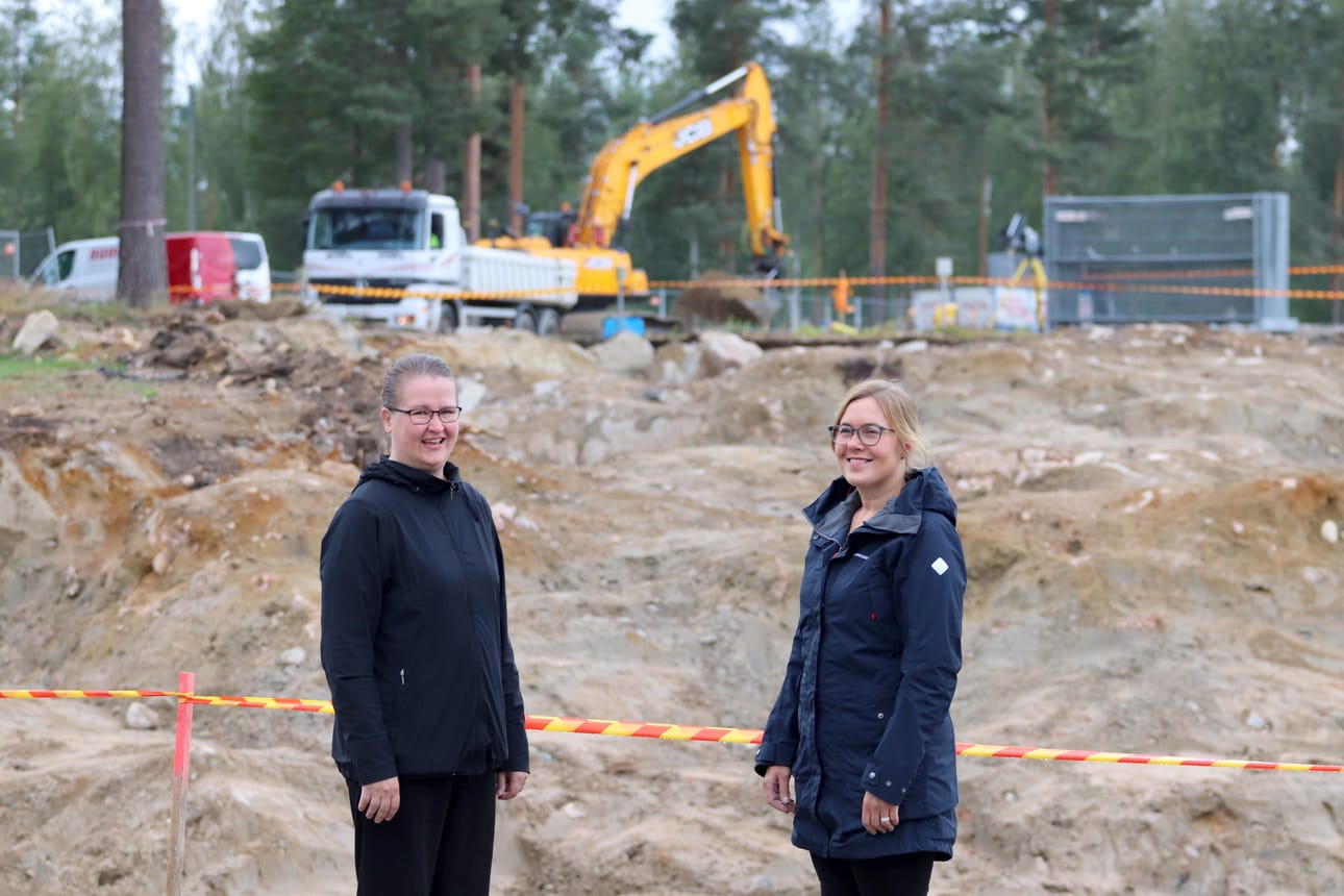 Kaupunginhallituksen puheenjohtaja Anni-Inkeri Törmänen ja valtuuston puheenjohtaja Mari Kälkäjä seisovat Hyvän olon keskuksen tontin laidalla. Valtuustokauden alussa ei vielä ollut varmuutta siitä, miten kaupungin tilaongelmat tullaan ratkaisemaan, mutta kahden vuoden aikana valmistelutyö on tehty ja päätös rakentamisesta on johtanut jo tositoimiin .Kaksikko kiittelee uuden suunnittelun edenneen jouhevasti.