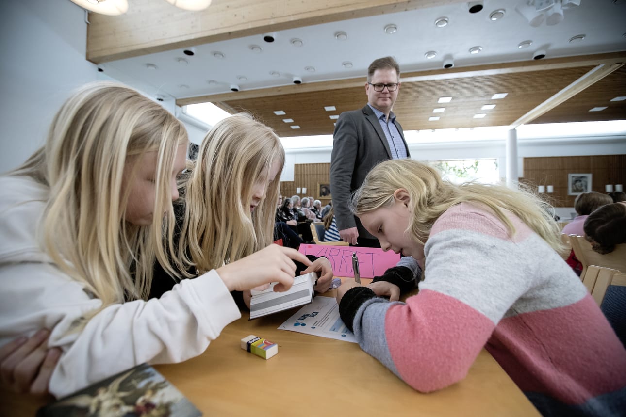Ruukin koulun Alina Pääkkö, Riina Kämäräinen ja Seela Terho miettivät visrivisan vastauksia. Taustalla kanttori Jouni Pietiläinen.