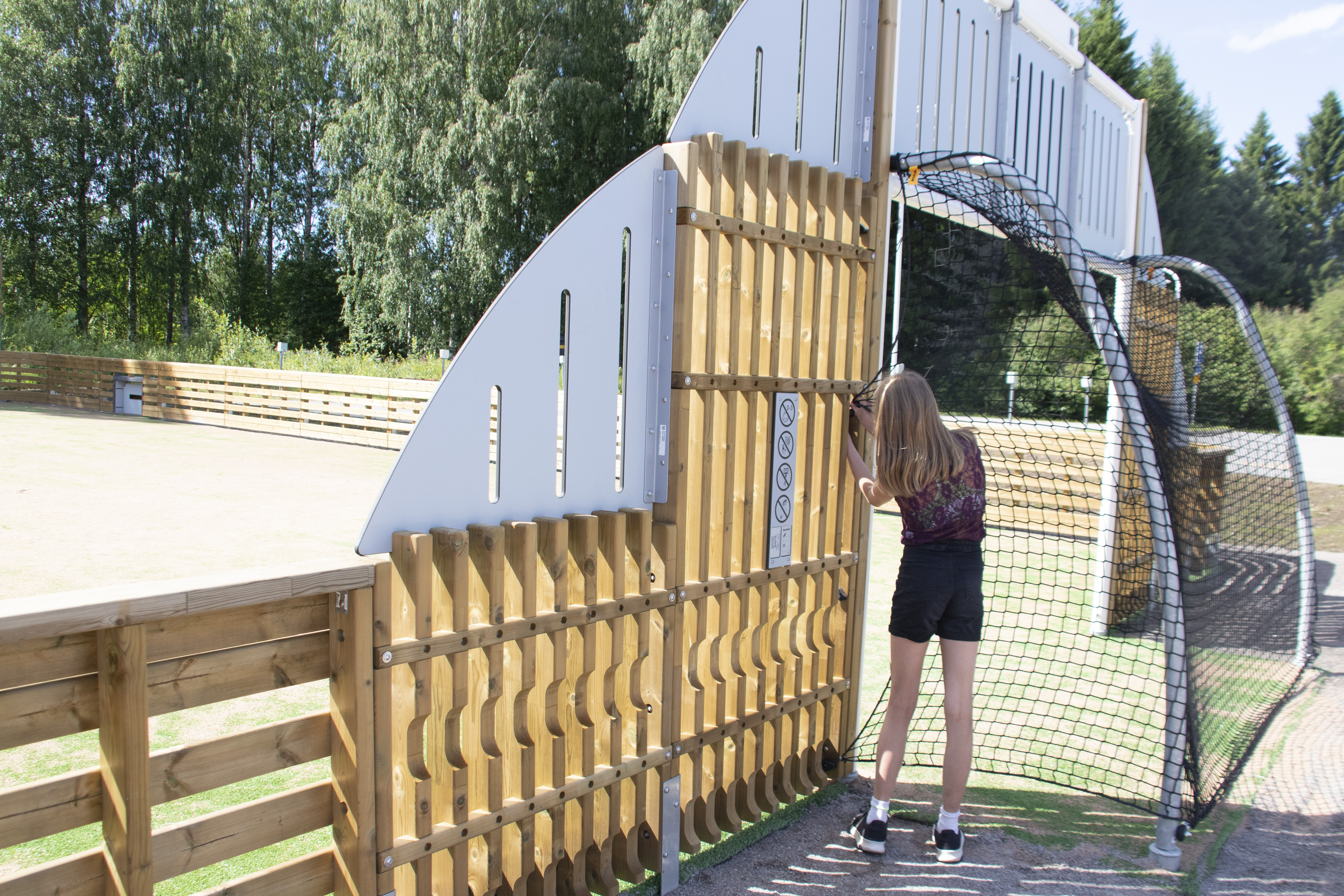 Senja Karpppimaa näytti, kuinka liikuntahallin pihaan rakennetulle, pallopeleihin tarkoitetulle monitoimiareenalle on käynti maaliverkon sivusta.