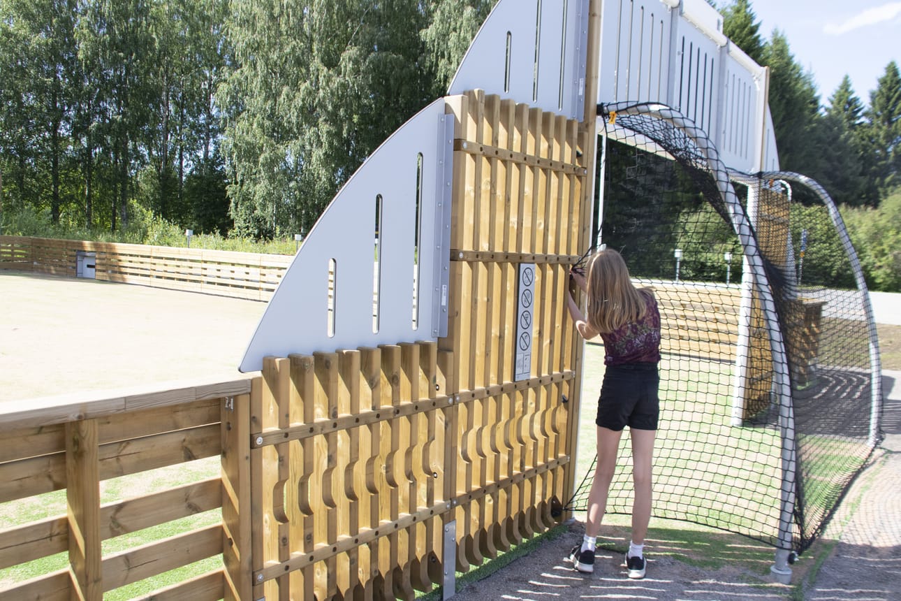 Senja Karpppimaa näytti, kuinka liikuntahallin pihaan rakennetulle, pallopeleihin tarkoitetulle monitoimiareenalle on käynti maaliverkon sivusta.