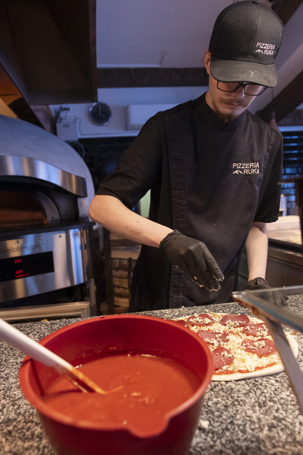 Pizzeria Rukan kokki Tuukka Takkunen ripottelee sinihomejuustoa Renna di bosco -pizzan päälle.