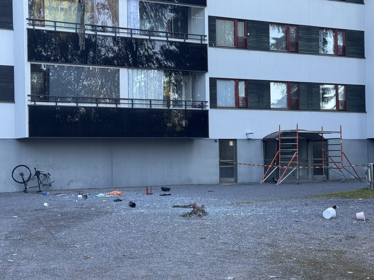 Kerrostalon pihamaa on täyttynyt lasinsirpaleista ja muusta tavarasta.