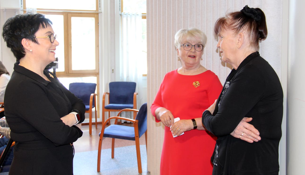 Eila Arvio (oik.) keskustelemassa Riikka Moilasen ja Marja Irjalan kanssa karjalaisista juurista.