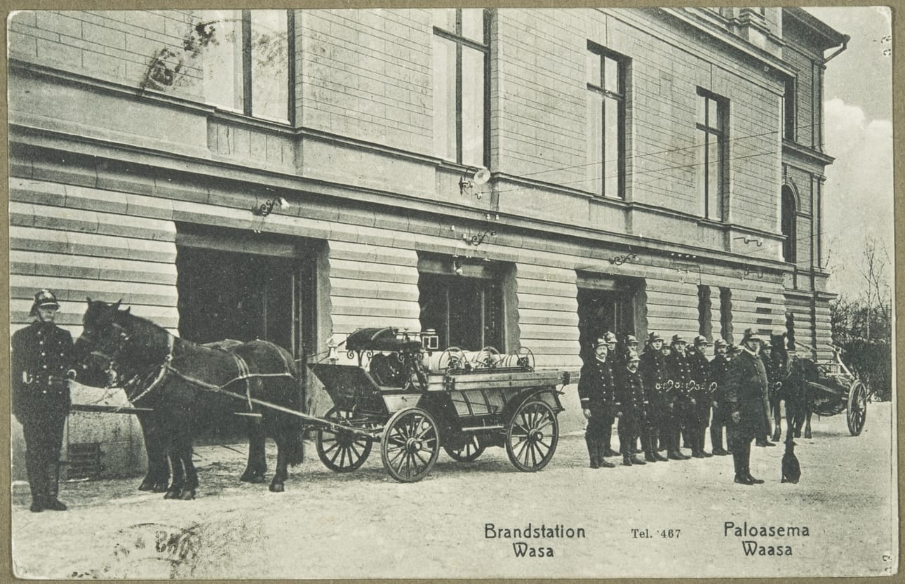 Palokunta talliensa edessä noin 1910. Oikealla palomestari Arell koirineen. Arkistokuva.