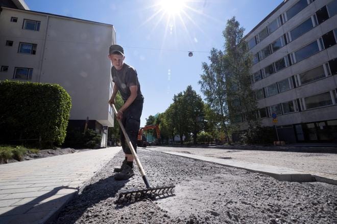 Simon Vestman tasoittaa Koulukadun uuden kivetyksen pintaa auringossa. Taukoja mies ei ole tavallista enempää helteillä pitänyt. KUVA: JARNO PELLINEN