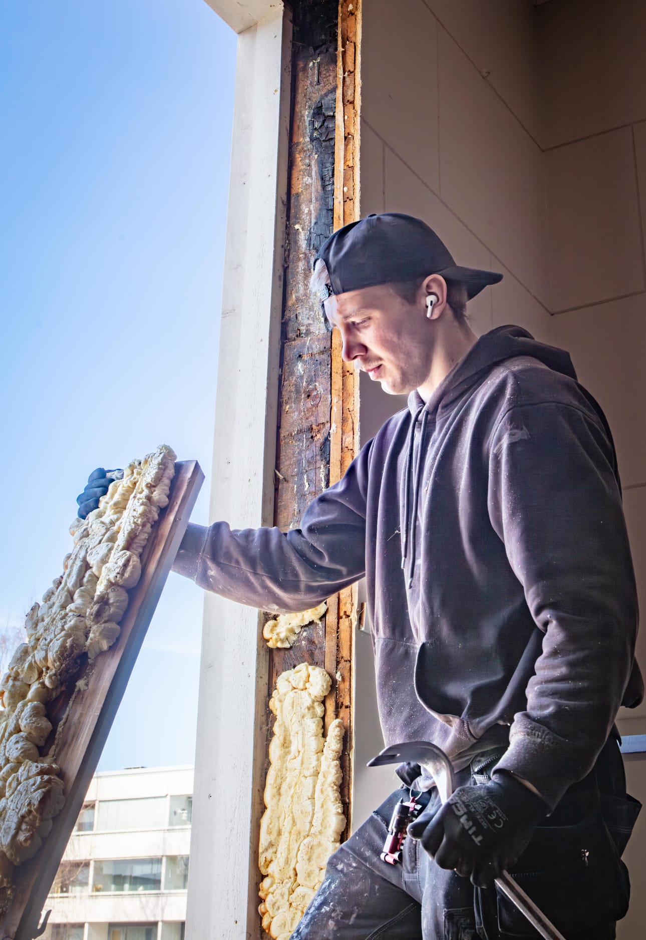 Hannes Lehto purkaa vaihdettavan ikkunan rakenteita. Alta paljastuu yli 70 vuotta sitten tapahtuneen tulipalon jälkiä.