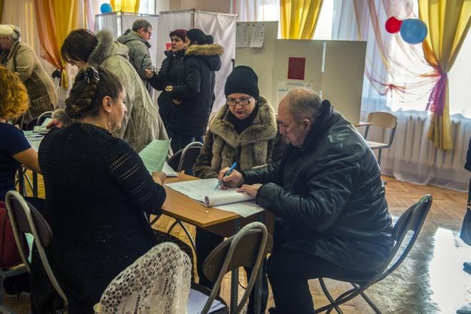 Äänestäjät täyttävät vaalilipukkeita avoimesti pöydällä Pietarin koulussa numero 189. Venäjän presidentinvaalit muistuttavat ulkoisesti länsimaisia, mutta prosessissa on useita epäilyttäviä kohtia. KUVA: Markku Saksa