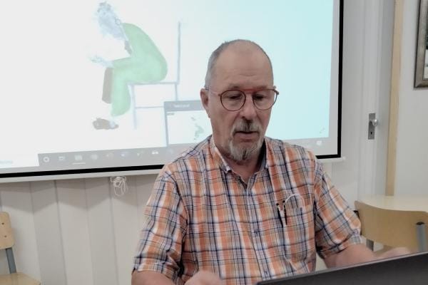 Jorma Turpela uhkuu intoa päästä opastamaan arjen digitaitoja niitä tarvitseville. Turpelan taustalla näkyvän satiirisen Nitro digikerhon logon on tehnyt hänen vaimonsa taiteilija Eva-Riitta Turpela. KUVA: MAIJA ALAFOSSI