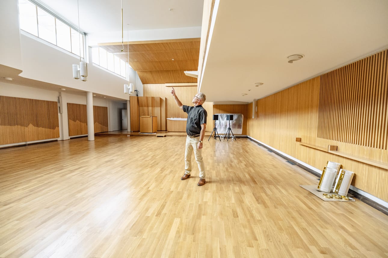 Ari Auranen esittelee uudistunutta seurakuntasalia. Seinäpinnat ovat vanhoja, mutta nekin on irrotettu ja puhdistettu. Myös alkuperäiset valaisimet on puhdistettu ja tarvittaessa kunnostettu.