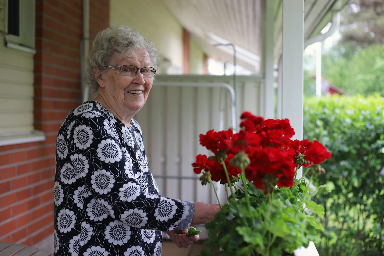 Iloinen ja virkeä Kaarina Vuoti rakastaa kukkia. Hänen takapihansa terassia koristavat pelargoniat, ja pihan puolella on muutamia pensaita.