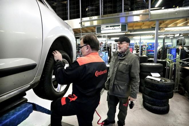 Seinäjokelainen Heikki Kotiranta seuraa, kun Aulis Haavisto vaihtaa hänen autoonsa nastarenkaat alle. Kotirannan mukaan isojen valmistajien renkaat ovat nykyään melko tasalaatuisia. Kuva: Jouko Hänninen