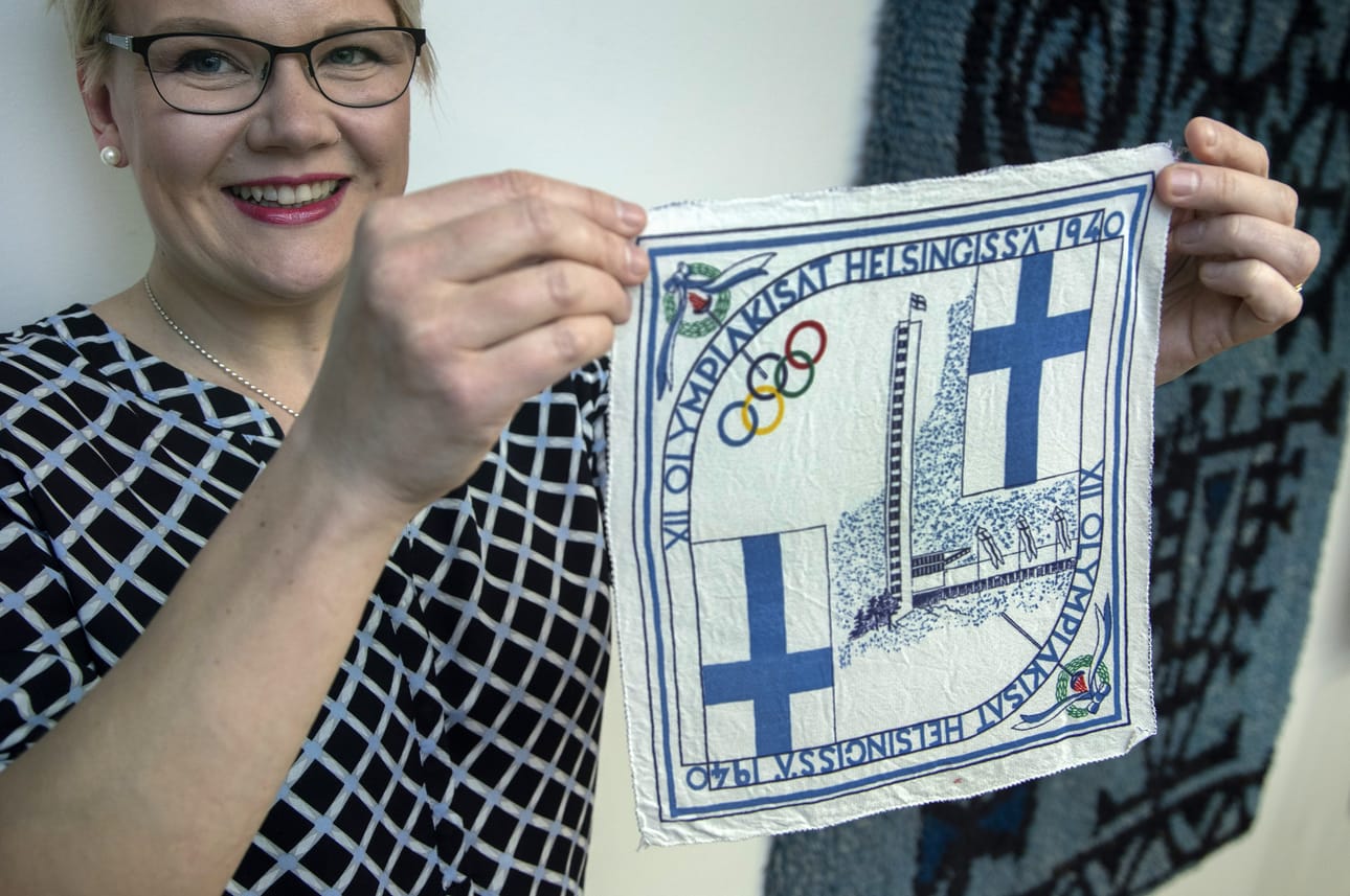 Suomessa piti olla olympialaiset vuonna 1940. Talvisota sotki kuviot. Lotat olivat ehtineet valmistaa tuhansia muistonenäliinoja. Ruotsin lotat tulivat apuun ja myivät ne länsinaapurissa. Saaduilla varoilla rakennettiin talo lottien virkistyskäyttöön. Toiminnanjohtaja Anne Suominen käsittelee silkkistä liinaa varovaisesti.